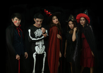 Group of 5 men and women dress in Halloween costume and zomby, witch make up against black background.