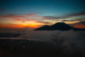 A splendid horizon view of kintamani volcano peak and golden sky from the top of the Mount Batur during the sunrise with fog