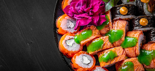 set of sushi roll with salmon, avocado, cream cheese, cucumber, rice, caviar, eel, tuna in plate on black wooden table background