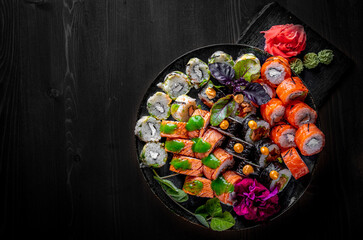 set of sushi roll with salmon, avocado, cream cheese, cucumber, rice, caviar, eel, tuna in plate on black wooden table background
