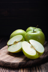 a green Apple cut into two slices on a cutting Board on a wooden background