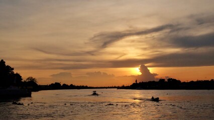 Fototapeta na wymiar Silhouette sunset with riverscape view and golden sky at dusk, Prakkret NONTHABURI Thailand