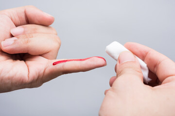 Use a cotton wool to wipe the blood at the wound on fingertips that are bleeding.