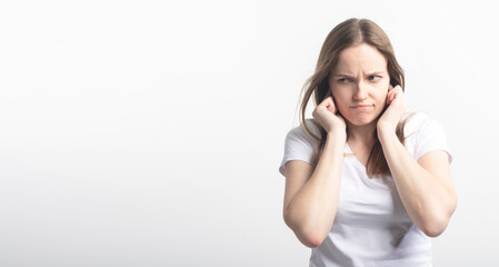 Concerned frustrated young female in feeling fatigue, squinting and close her ears with fingers...