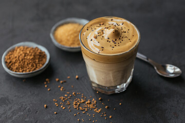 Glass of Iced Dalgona Coffee, trendy fluffy creamy whipped coffee and milk on dark background.