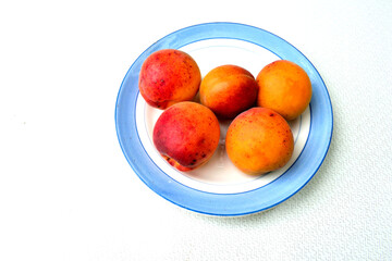 five large apricots on a plate, close-up