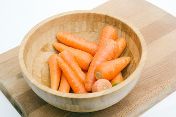 fresh carrots on wooden bowl