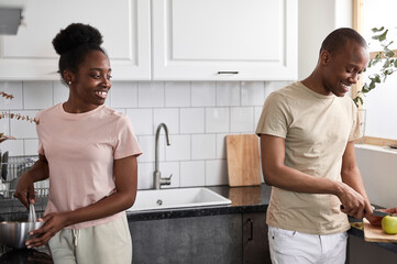 Obraz premium beautiful young black african couple have conversation in the kitchen, they cook together, preparing food as one team. friendly family concept