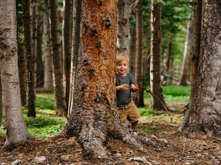 Little kid playing in the forest with sticks