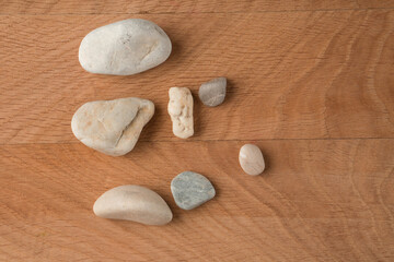 Fototapeta na wymiar Smooth stones, of various sizes, are scattered on a wooden board