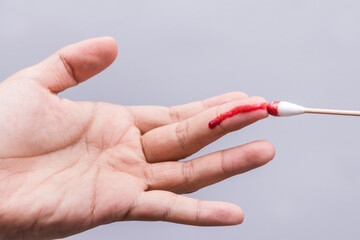 Use a cotton swab to wipe the blood at the wound on fingertips that are bleeding on white background.