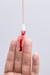 Use a cotton swab to wipe the blood at the wound on fingertips that are bleeding on white...