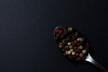 various types of pepper in a spoon on a dark background. hot seasonings for cooking.