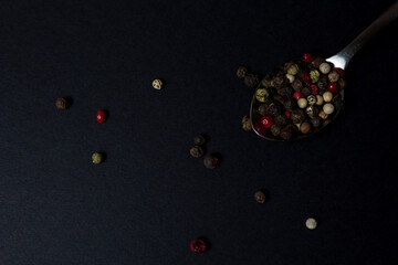 various types of pepper in a spoon on a dark background. hot seasonings for cooking.