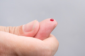 Blood drop on fingertip prepare for checking the glucose level with a glucometer for examining diabetes mellitus.