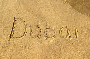 Dubai word on beach sand. Dubai city letters is written on a sand. Handwriting