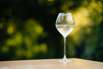 A glass of white wine outdoors at sunset. Exquisite white wine in a glass against the background of the garden