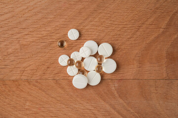 Fototapeta na wymiar A bunch of various medicines, pills lying around without packaging on a wooden board