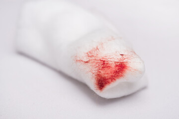 A cotton wool swab with blood stains after use, from cleansing the bleeding wound on a white...