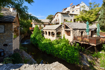 Fototapeta na wymiar Picturesque medieval stone buildings house cafes and restaurants with patios near the river Neretva in Mostar, Bosnia-Herzegovina