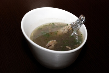 ribs with meat in the broth with some herbs served in the white bowl