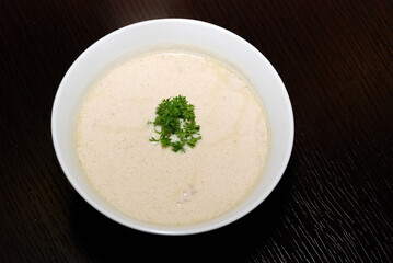 creamy soup in the white bowl and parsley in the middle