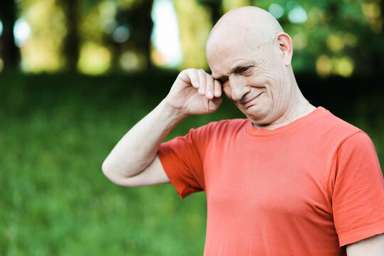 Close Up Portrait Of Senior Man Crying And Looking At Camera With Red Eyes. High Quality Photo