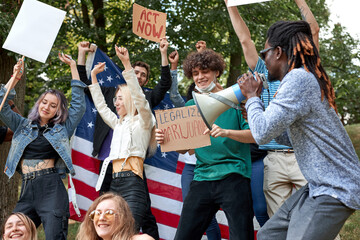 diverse mixed race people with posters agitating Marijuana being legal, group of youth in the park, holding placards and megaphone loudspeaker