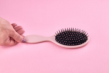 woman take a pink hairbrush isolated on a pink coral background with space. beauty hair accessory for hairstyle.