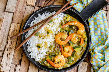 cuisine thaï : gambas au lait de coco , curry, dés de courgettes et oignons rouges avec du riz 