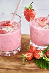 Strawberry milk shake in glass with straw and fresh berries on a white background