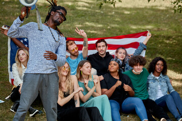 Fototapeta premium american mixed race youth sit on grass together and have fun, laugh, sing songs and talk with each other. happy young generation