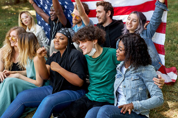 american mixed race youth sit on grass together and have fun, laugh, sing songs and talk with each other. happy young generation
