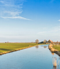 Fototapeta na wymiar Canal, field and farmhouse in Hindeloopen, Netherlands, Europe