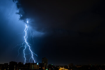 Bright flash of powerful lightning in the city at nighttime.