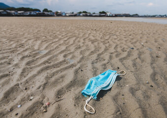 Used face mask dirty waste on the beach.