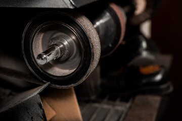 Grinder machine for shoes, cobbler shop. Dark ambience.