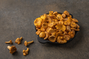 Raw fresh chanterelle fox mushrooms in a cast-iron frying pan on a wooden background. Copy space for text 