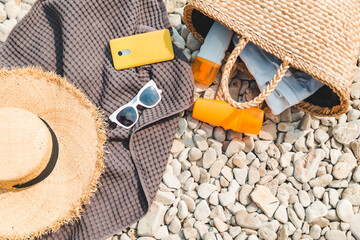 overhead view of beach stuff blanket with sun protection cream straw hat with bag