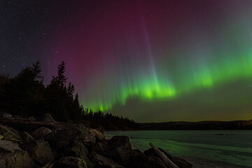Aurora Borealis or Northern Lights from a lake during a winter night in Canada