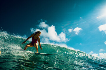 Professional Surfer Girl riding wave on surfing board under bright sun on background. - 365899176