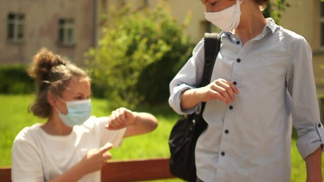 Masked students comply with safety rules during quarantine of coronavirus covid-19. Children disinfect their hands and greet non-contact. Contactless greeting