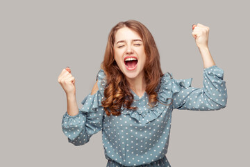 I am champion! Delighted happy enthusiastic girl ruffle blouse raising fists shouting for joy...