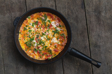 frying pan with an omelette on a wooden dark background. View from above