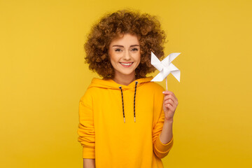 Origami hand mill. Portrait of happy curly-haired woman in urban style hoodie smiling carefree and...