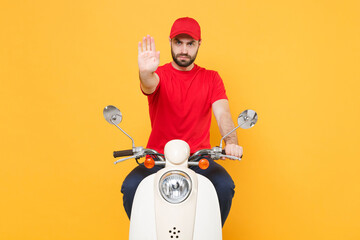 Delivery man in red cap t-shirt uniform driving moped motorbike scooter isolated on yellow background studio Guy employee working courier Service quarantine pandemic coronavirus virus covid-19 concept