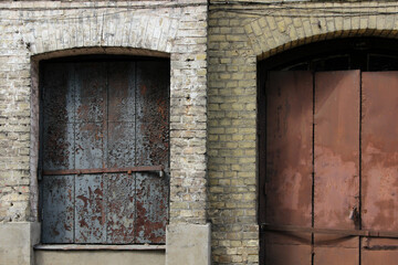Plakat Rusted metal door and closed window shutter on the abandoned building facade.