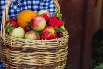 fruit basket in the hands of a girl on a wooden background