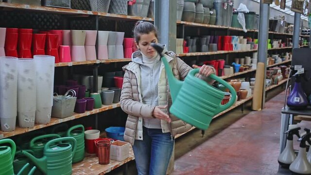 Woman chooses watering can for watering plants in store