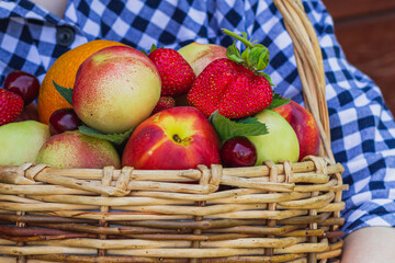 fruit basket in the hands of a girl on a wooden background